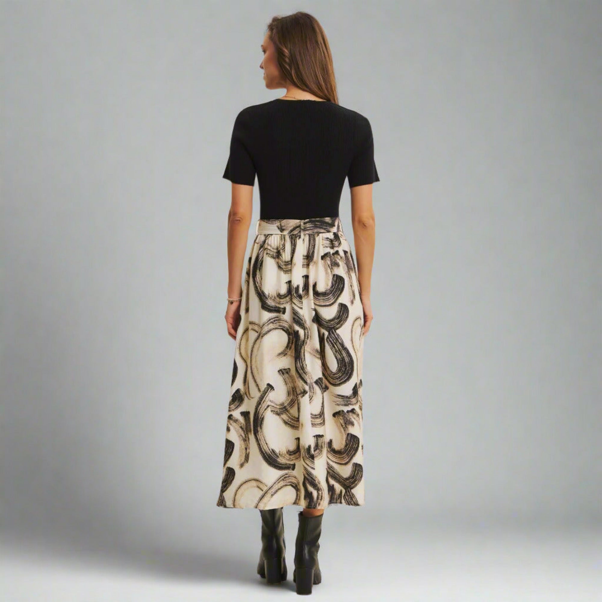 Woman wearing a black top and patterned skirt on a gray background