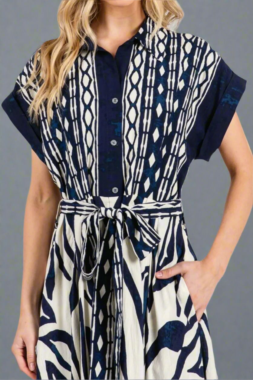 Woman wearing a patterned dress with a belt against a gray background