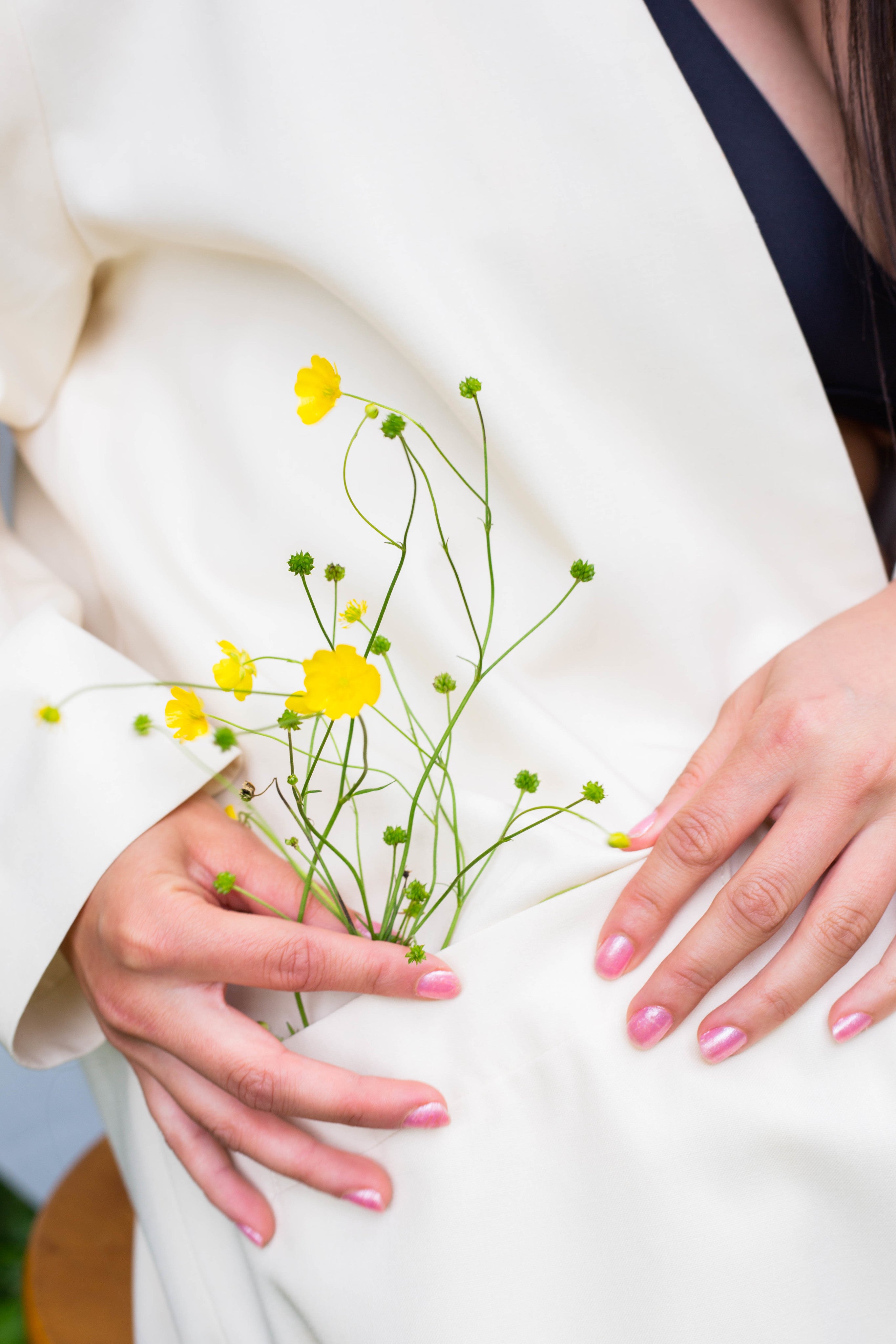 hands-holds-buttercup-flowers-in-the-pocket-of-their-coat.jpg