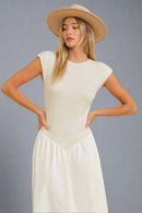Woman wearing a beige top and white pants with a beige hat on a beige background
