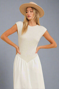 Woman wearing a beige top and white pants with a beige hat on a beige background