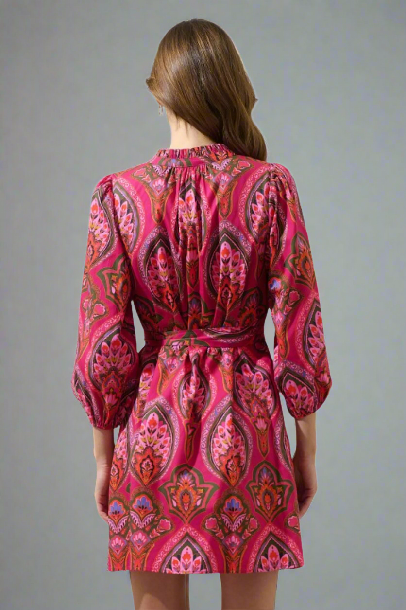 Woman wearing a pink and red patterned dress on a white background