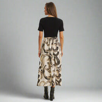 Woman wearing a black top and patterned skirt on a gray background