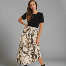 Woman wearing a black top and patterned skirt on a plain background