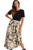Woman wearing a black top and patterned skirt on a plain background