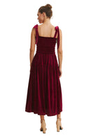 Woman wearing a burgundy dress with bow straps on a beige background