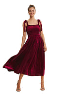Woman wearing a burgundy velvet dress with lace details on a beige background