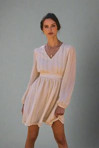 Woman in a white dress standing in front of gray backdrop