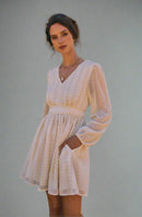 woman wearing cream dress with hands in pocket