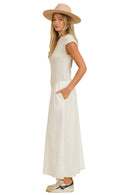 Woman wearing a white dress and beige hat against a beige background