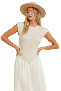 Woman wearing a beige top and white pants with a beige hat on a beige background