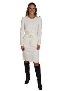 Woman wearing a white dress with long sleeves and black knee-high boots on a gray background