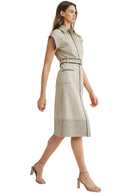 Woman wearing a beige sleeveless dress with a belt on a light gray background