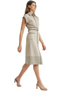Woman wearing a beige sleeveless dress with a belt on a light gray background