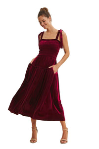 Woman wearing a burgundy velvet dress on a plain background