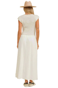 Woman wearing a white dress and beige hat against a beige background